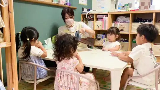 テーブルで水分補給をする子どもたちと保育士